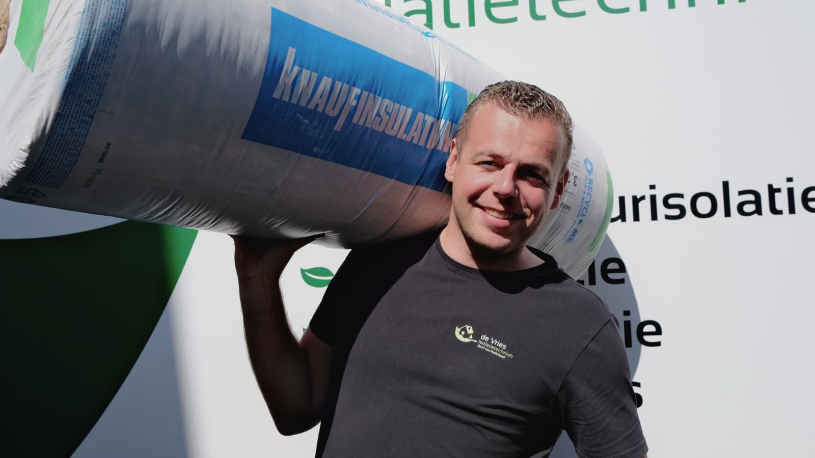 Medewerker van De Vries Isolatie draagt een rol isolatiemateriaal op zijn schouder