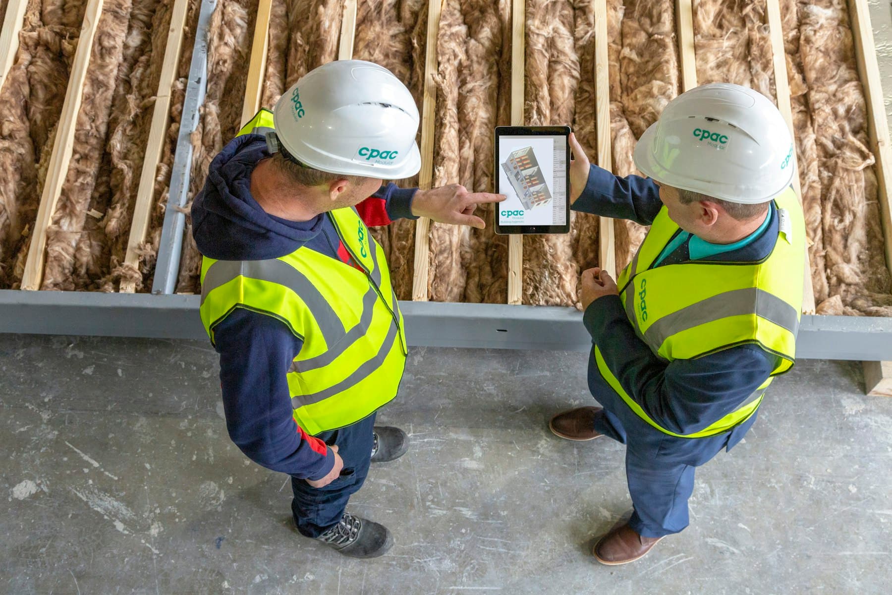 Twee bouwers bekijken een tablet tussen het isolatiemateriaal