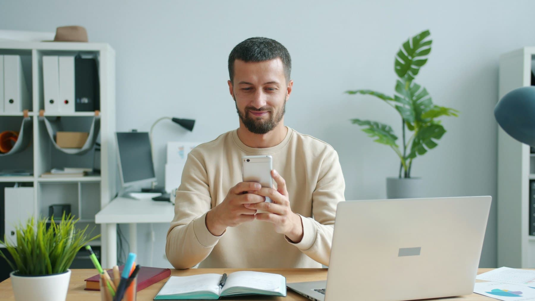 Ondernemer kijkt lachend naar een melding op zijn telefoon